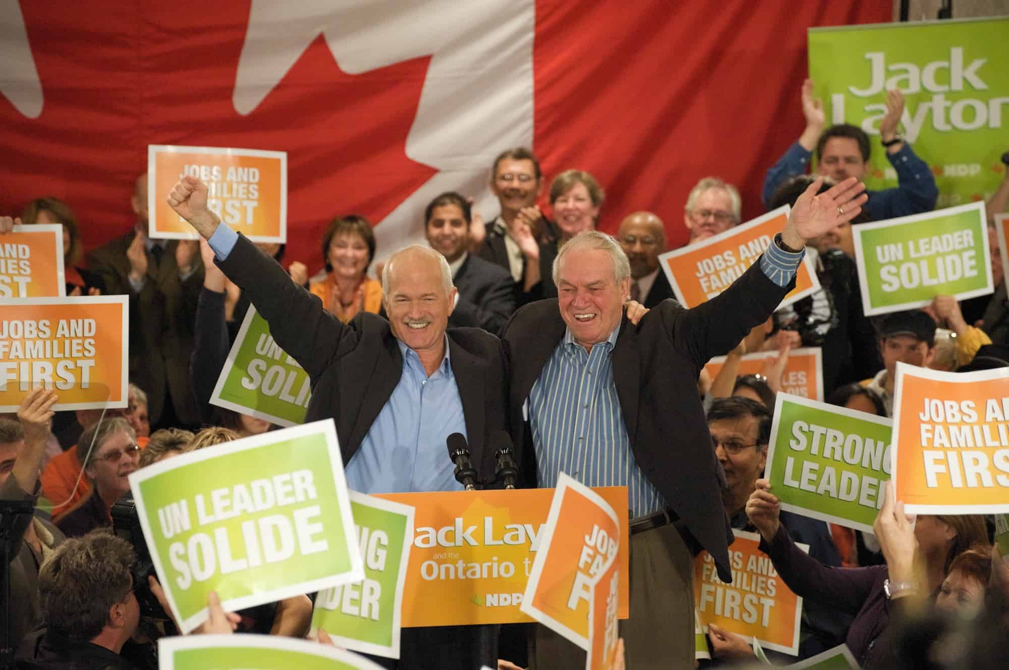 Jack Layton with Ed Broadbent during the 2008 federal election on stage among a crowd of supporters.