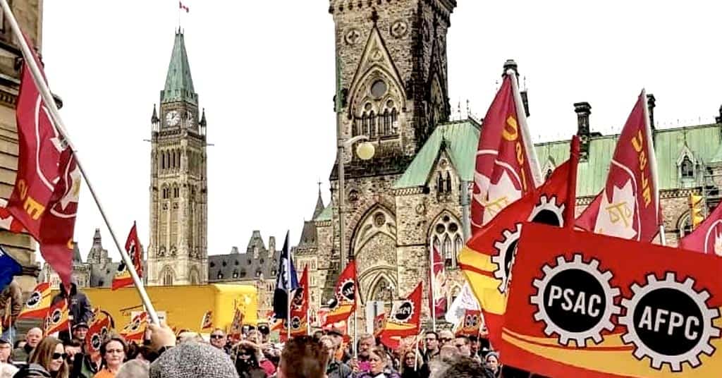 PSAC union members with flags march on Parliament Hill in Ottawa.