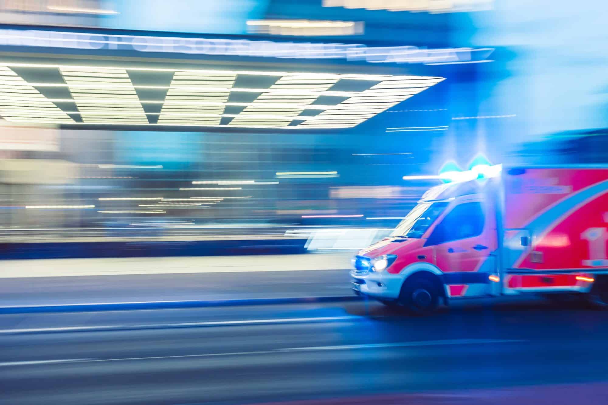 An ambulance speeds by quickly down a street.