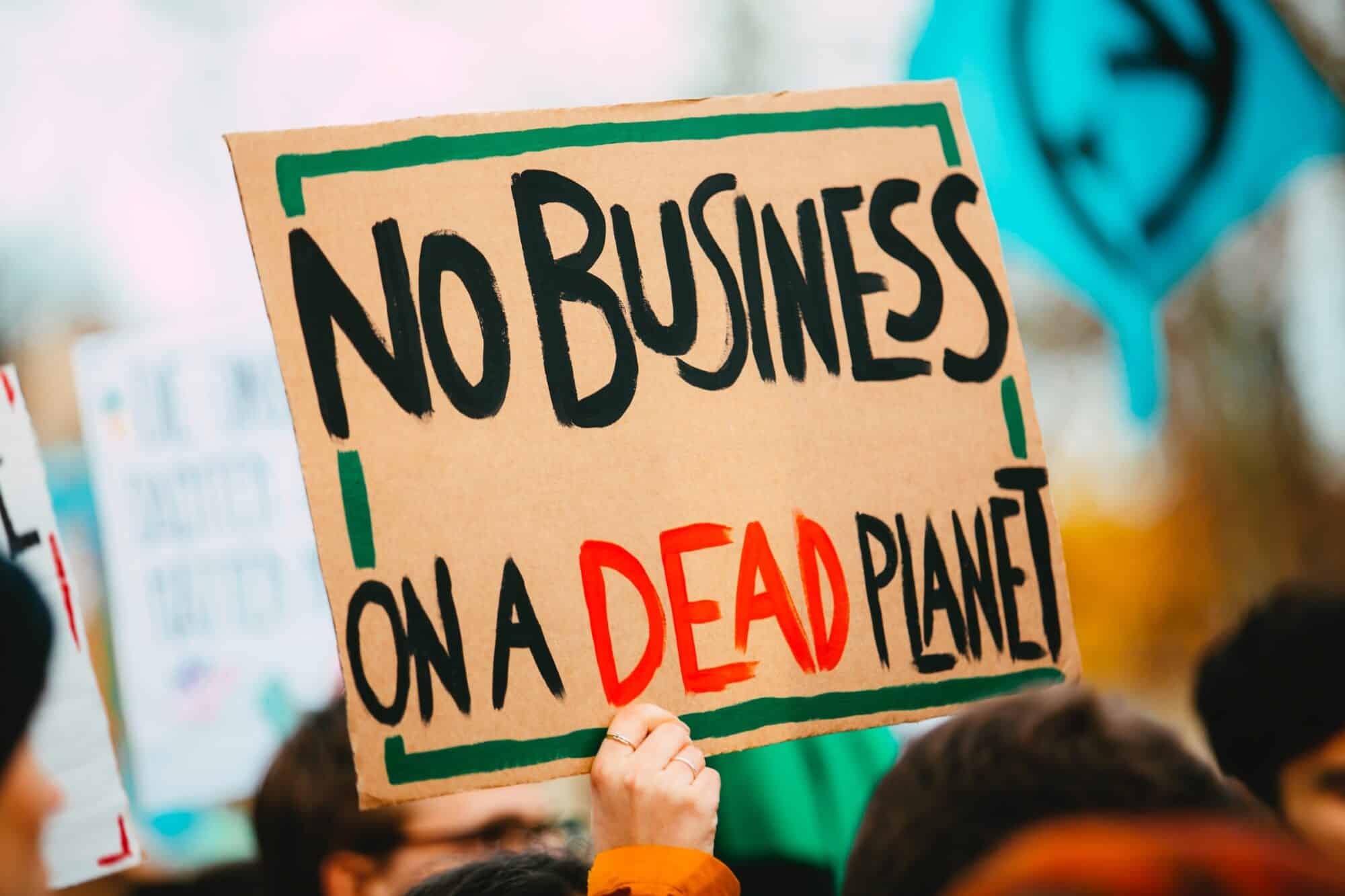A climate protester holds up a sign that reads "No business on a dead planet".