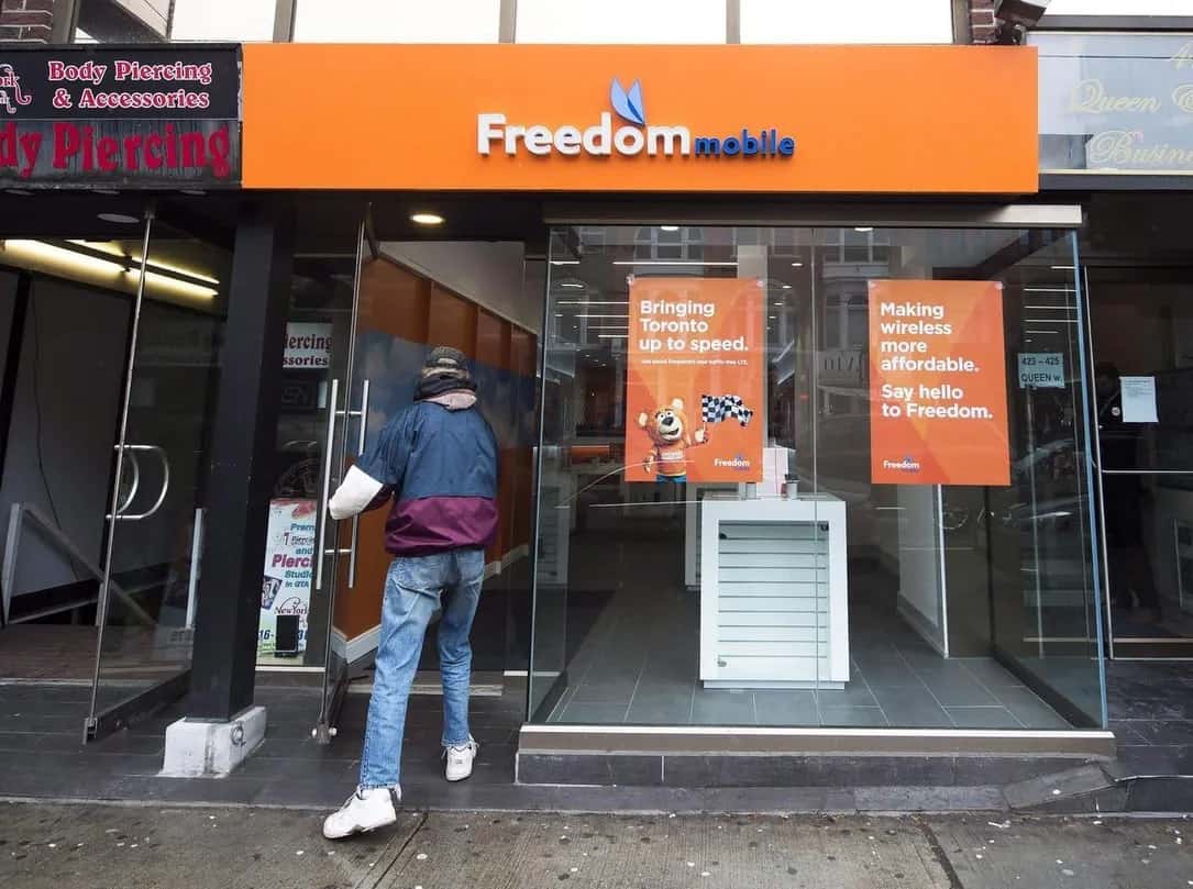 A customer enters a Freedom Mobile storefront on a city street.