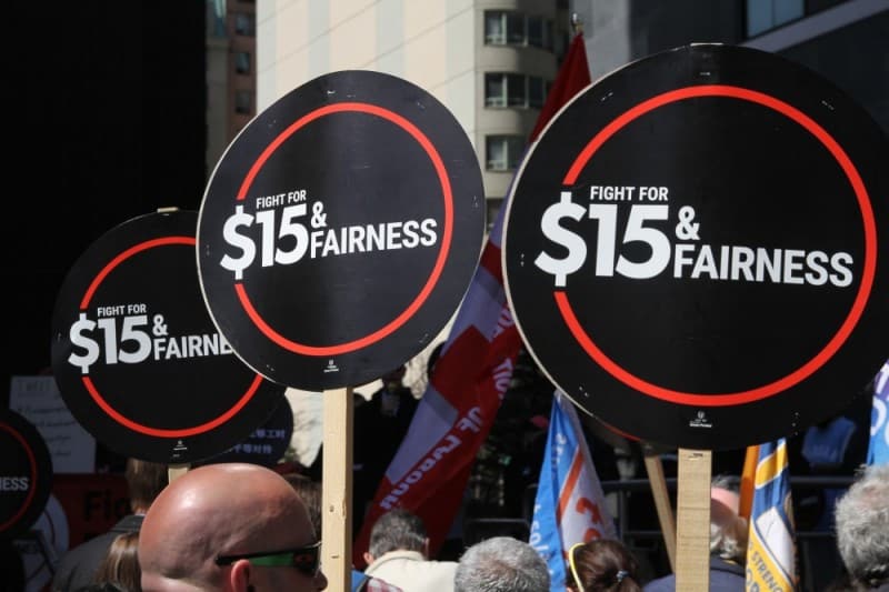 Signs at a rally calling for "$15 & Fairness".