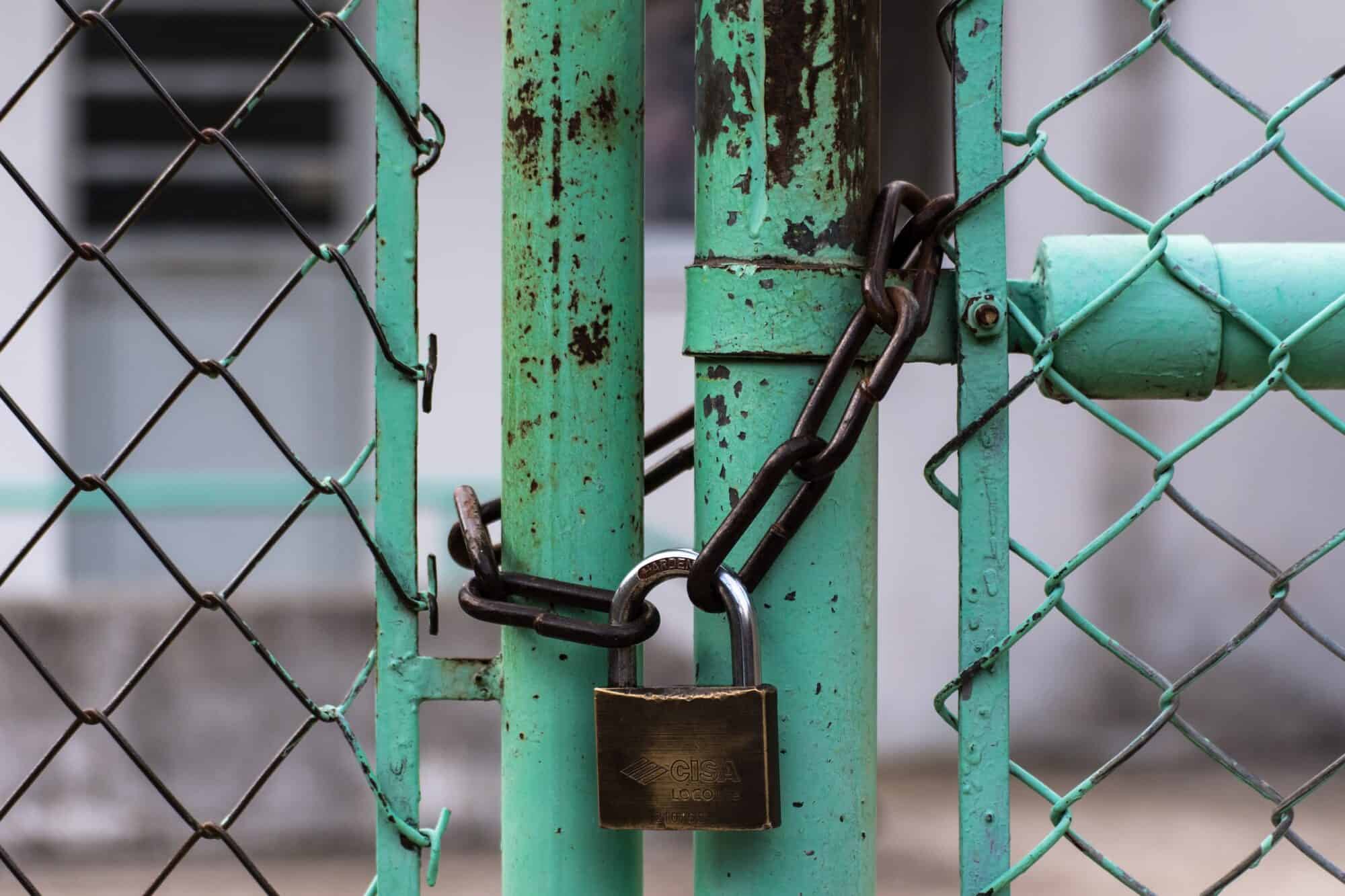 A steel fence gate is locked by a chain.