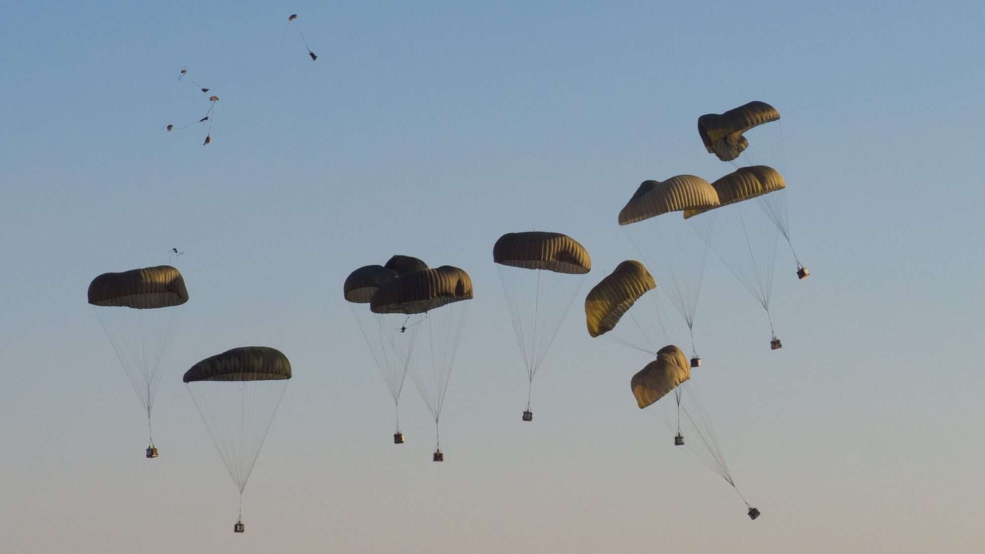 Boxes of supplies are parachuted from the sky.