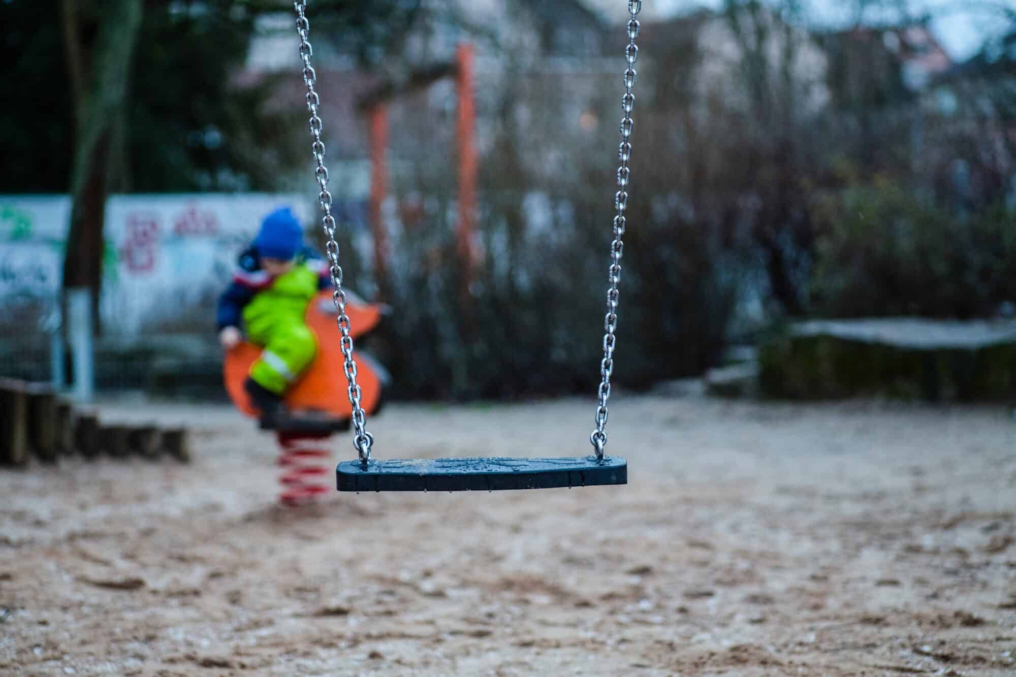 An empty swing in a child's playground.