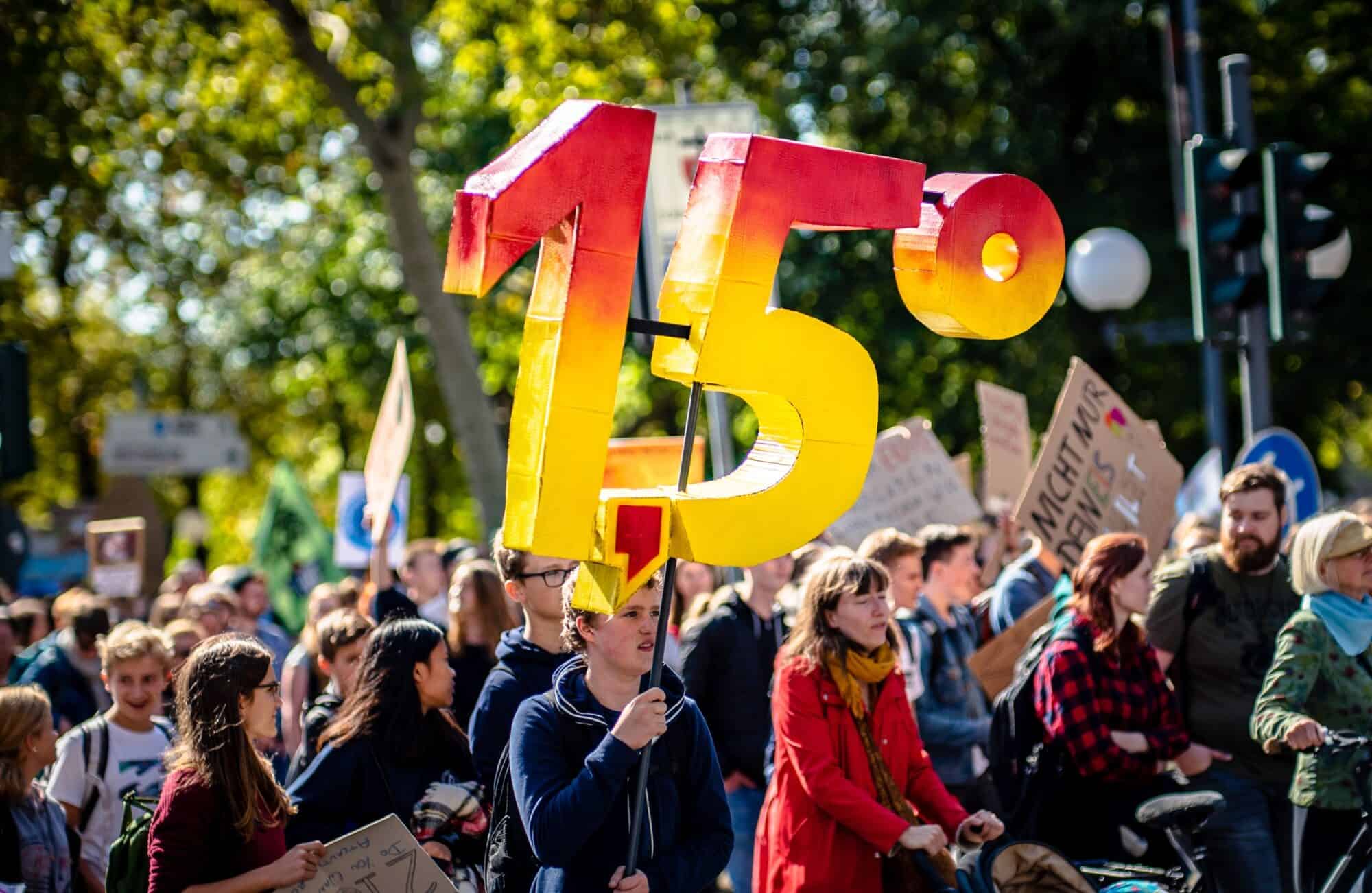 A climate protestor holds up a sign that says '1.5 degrees' referring to the limit of global average temperature change until irreversible catastrophic climate change.