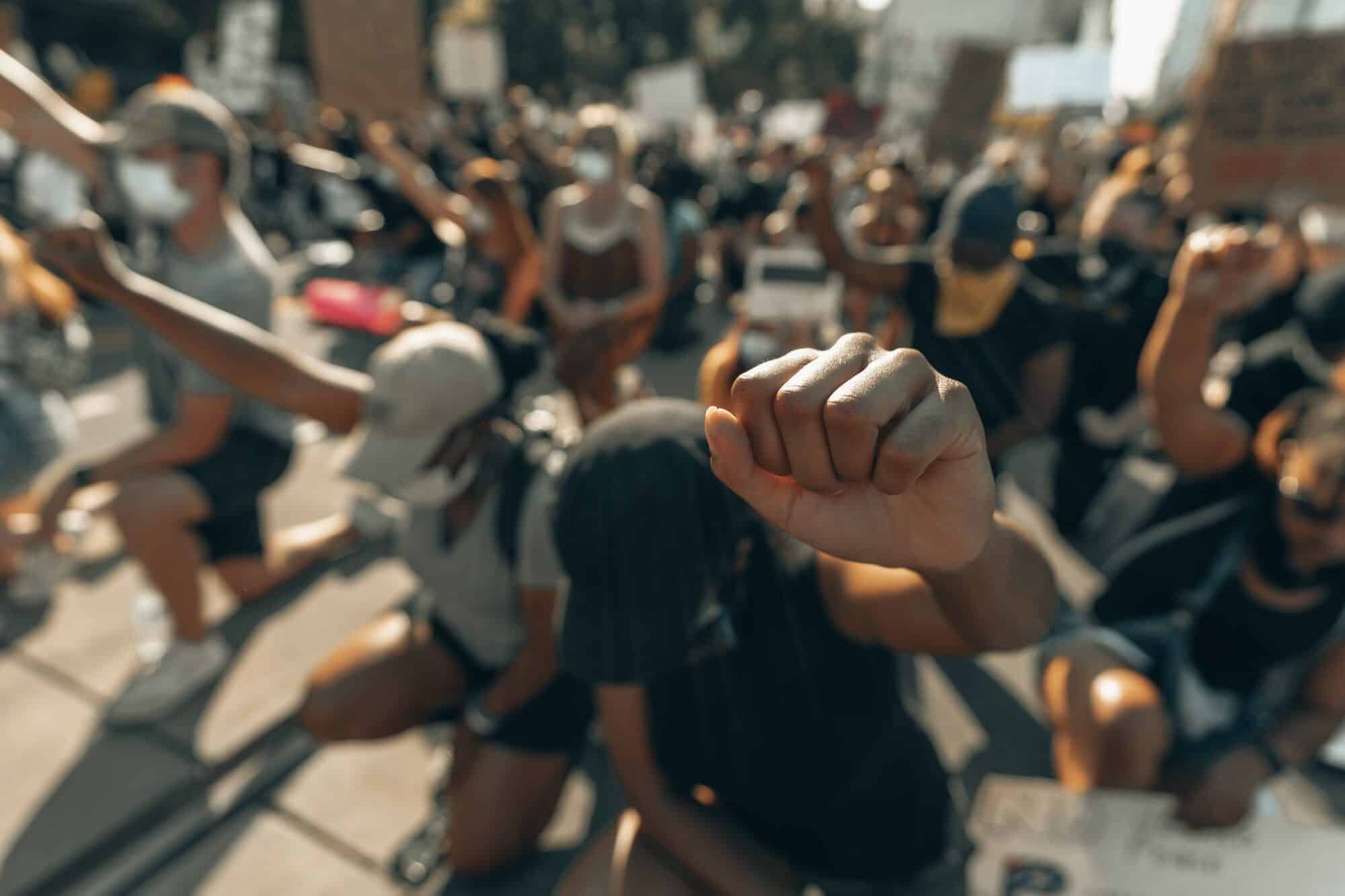 Black Lives Matter protestors kneel and raise fists in protest against police violence.