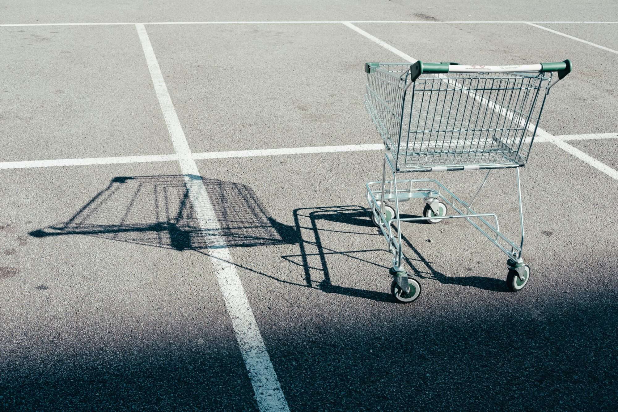 An empty shopping cart sits empty and alone in a parking lot.