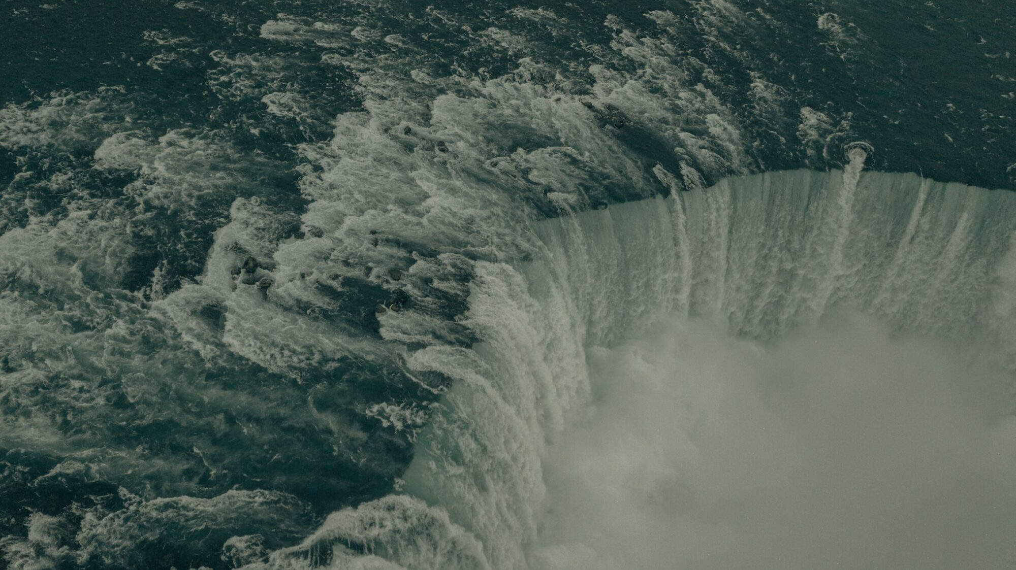 Overhead photo of Niagara Falls spilling over into the Niagara River.